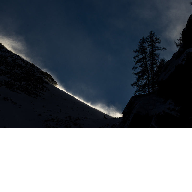 Avondzon verlicht de opwaaiende sneeuw