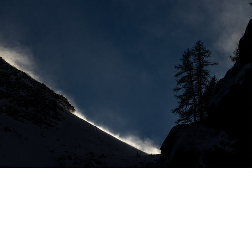 Avondzon verlicht de opwaaiende sneeuw