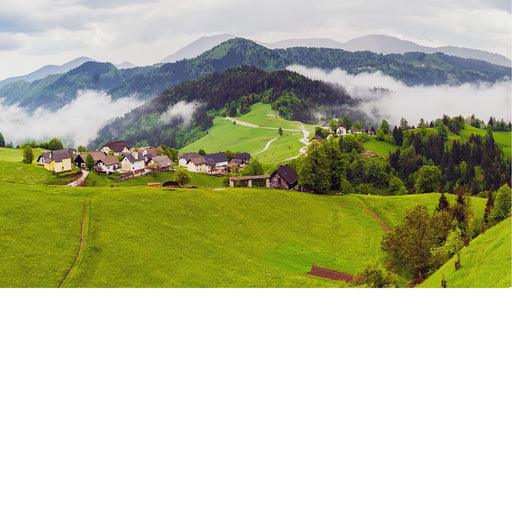 Een glooiend heuvellandschap wordt gedeeltelijk omhuld door laaghangende mist, terwijl het frisse groen en de zachte lichtinval zorgen voor een schilderachtige en serene sfeer. De combinatie van natuur, reliëf en wolkenslierten maakt dit een rustgevend landschap.