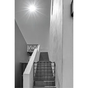 Zwart-witfoto van een trap en witte muren met een zon die straalt in de lucht, modern en minimalistisch.