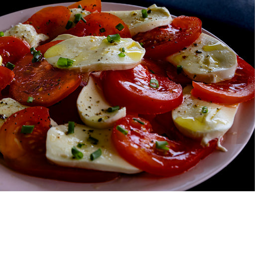 Close-up van een kleurrijke Caprese salade met tomaten, mozzarella, olijfolie en kruiden.