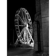 Zwart-witfoto van een groot reuzenrad met verlichting tegen een donkere nachtelijke lucht.