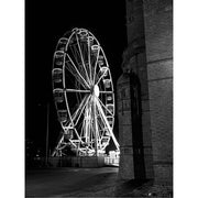 Zwart-witfoto van een groot reuzenrad met verlichting tegen een donkere nachtelijke lucht.