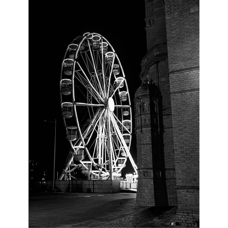 Zwart-witfoto van een groot reuzenrad met verlichting tegen een donkere nachtelijke lucht.