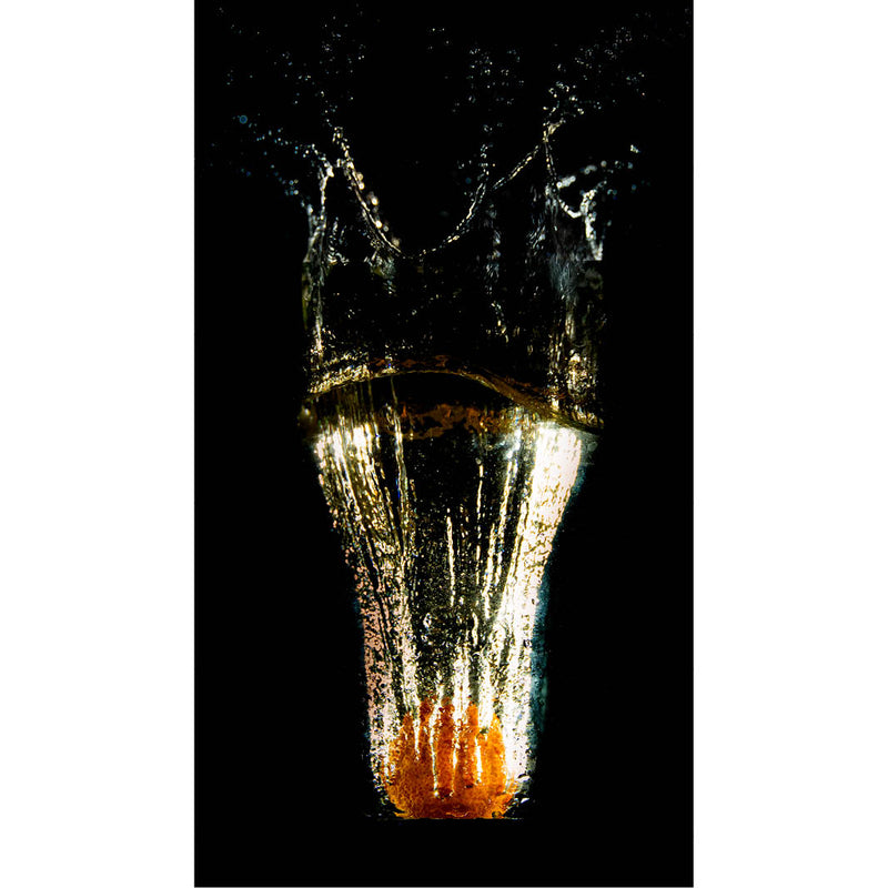 Dynamische opname van een sinaasappel die in water valt, met spectaculaire spetters en belichting tegen zwarte achtergrond.