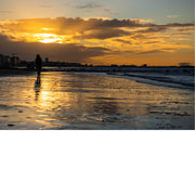 et strand met een warme zonsondergang en reflecties op nat zand.