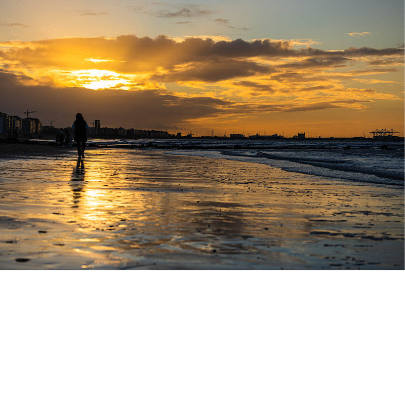 et strand met een warme zonsondergang en reflecties op nat zand.