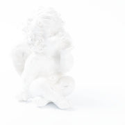 De foto toont een witte engelenfiguur die in een zachte high-key belichting volledig opgaat in een bijna totaal witte achtergrond. 