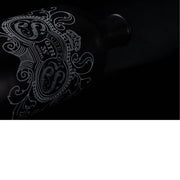 De foto toont een donkere, stijlvolle low-key opname van een fles gin, waarbij vooral het sierlijke etiket op de voorgrond komt. Door de minimale belichting worden enkel de fijne witte lijnen van het decoratieve ontwerp zichtbaar, terwijl de rest van de matte, zwarte fles bijna volledig in de schaduw verdwijnt.