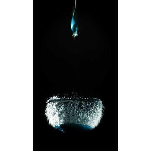 Een dichte wolk van waterdruppels barst naar buiten op het exacte moment dat een met water gevulde ballon openspat. Het bovenste gedeelte van de ballon schiet als een kleurrijke, vervormde vorm omhoog, terwijl de watermassa nog heel even haar originele contour behoudt. 