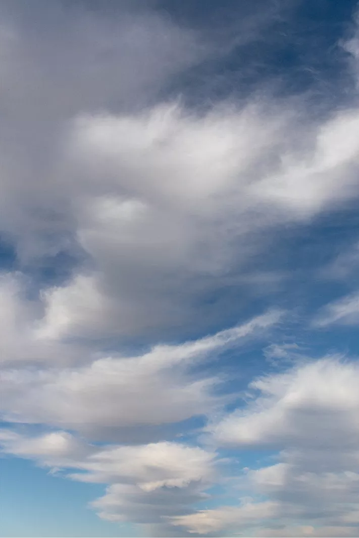 Witte en grijze golfwolken in strepen tegen een blauwe lucht