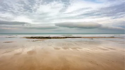Uitgestrekt zandstrand onder een indrukwekkende wolkenlucht, de foto