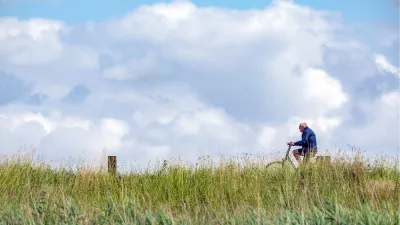 Fietser op de dijk door het hoge gras, de foto