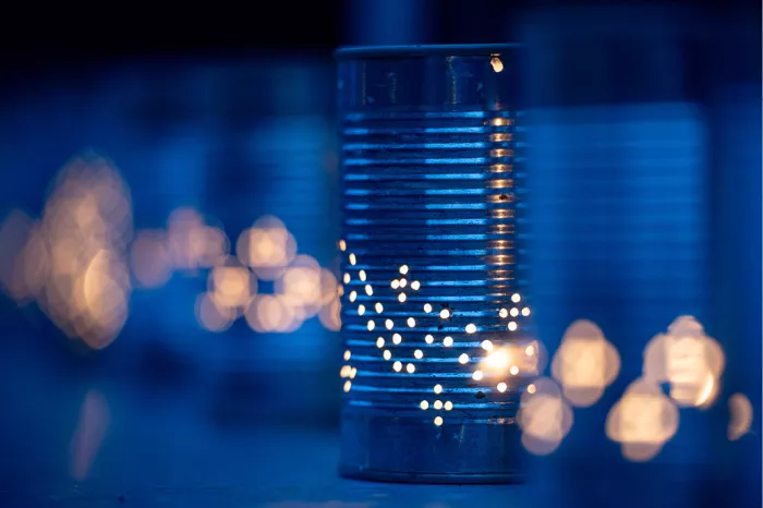 Blauw geperforeerd blikje met kaarslicht en warme bokehlichtjes erachter