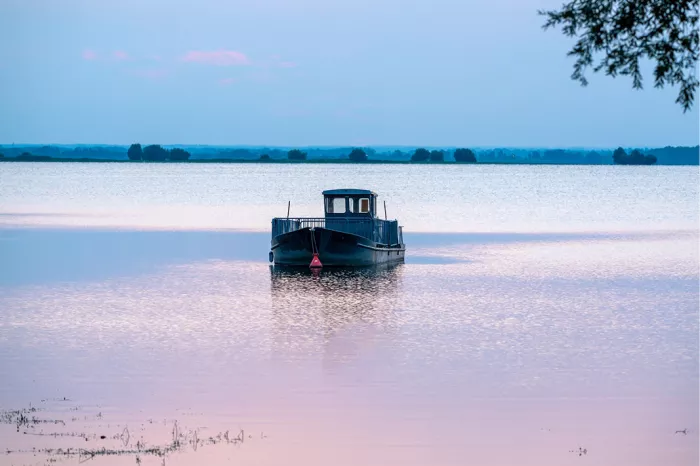 Kleine boot op een spiegelglad meer in blauwe en roze avondtinten