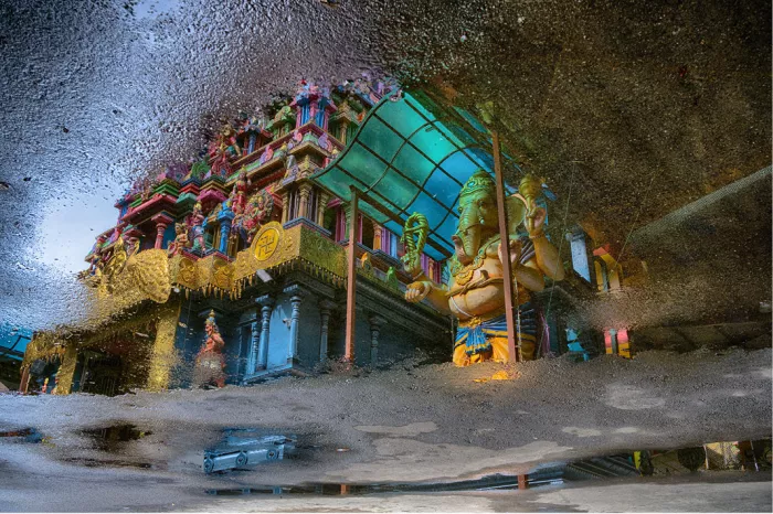 Spiegelbeeld in een plas van een kleurrijke hindoetempel met een groot beeld van Ganesha in Negombo, Sri Lanka
