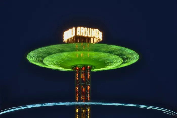 Draaiende kermisattractie vormt een groene lichtschijf rond een verlichte toren