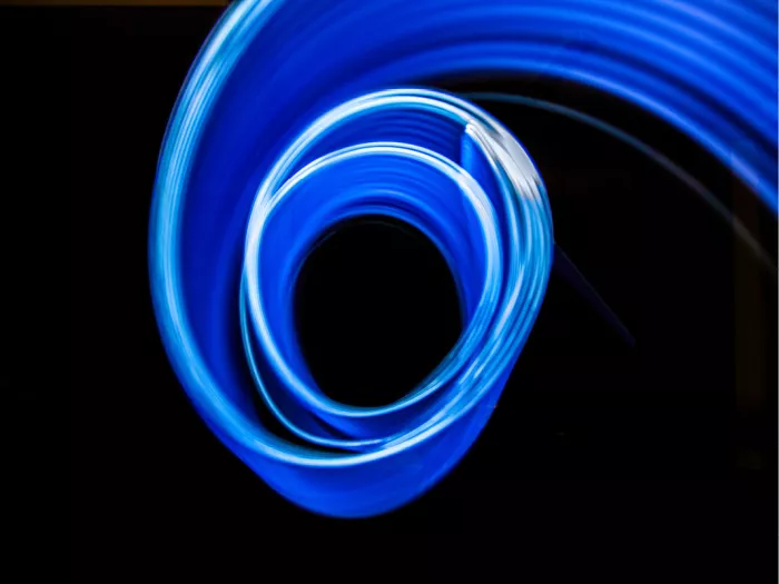 Blauwe lichtspiraal getekend met licht tegen een zwarte achtergrond