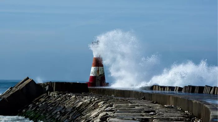 Rood-witte boei op een pier met een hoog opspattende golf