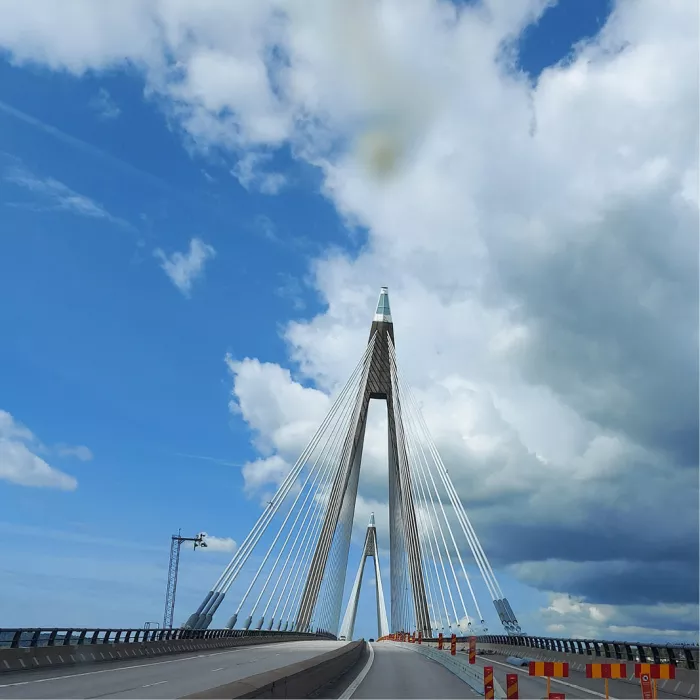 Tuibrug met hoge pylonen en kabels onder blauwe lucht met witte wolken