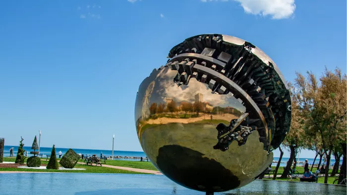 Glanzende bronzen bol met opengebroken binnenkant op een zonnige promenade