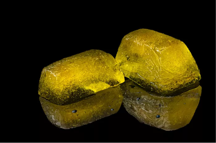 Twee amberkleurige ijsblokken met spiegeling op een zwart oppervlak