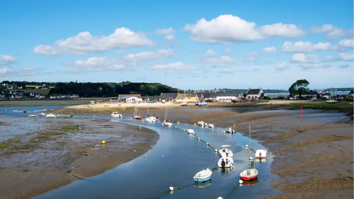 Bootjes in een kronkelende getijdengeul bij laag water in de baai van Morlaix onder een wolkenlucht