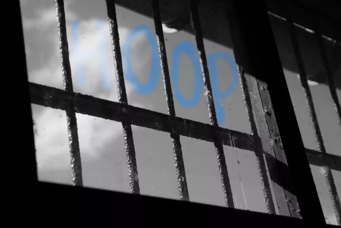 Tralievenster met het woord HOOP in blauw op het glas, verder in zwart-wit