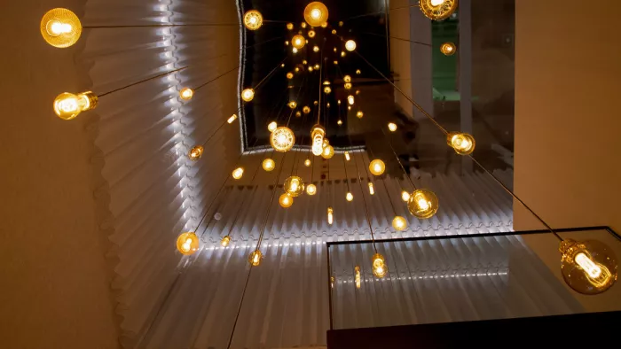 Tientallen hangende gloeilampen onder een plafond, van onderaf gezien in warm licht