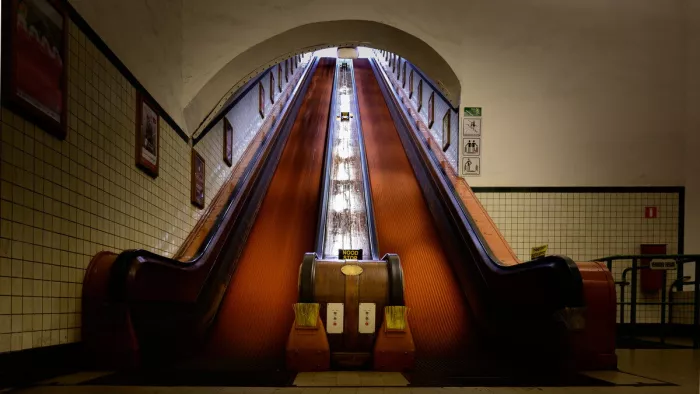Houten roltrap in de Sint-Annatunnel die steil omhoog loopt tussen tegelwanden, met een lichte opening bovenaan.