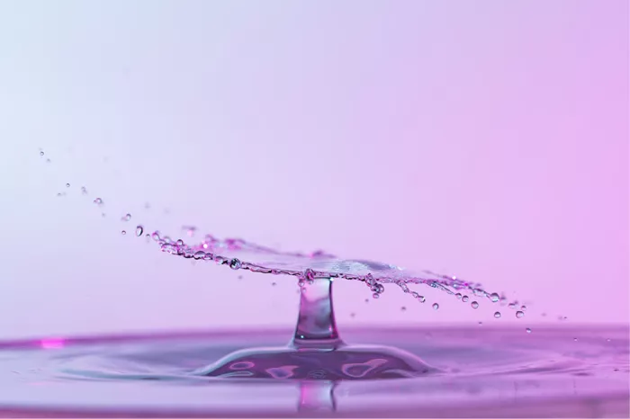 Waterzuil met een breed, plat scherm van opspattend water in roze en lila tinten