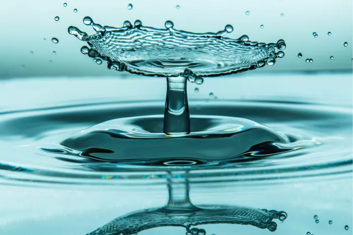 Waterscherm met druppelrand op een waterzuil en reflectie, in turquoise tinten
