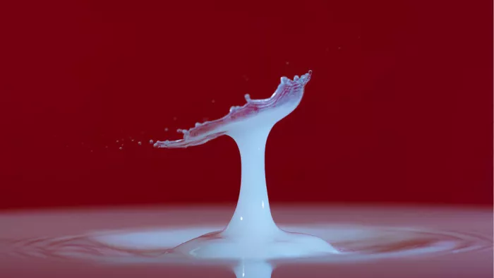 Witte melkzuil met een gekartelde schaal bovenaan, tegen een dieprode achtergrond