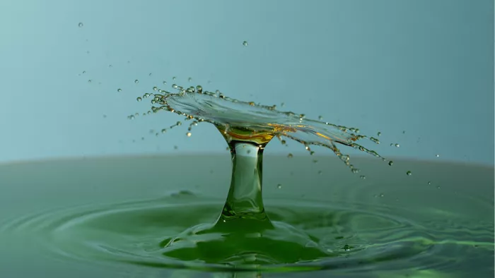 Breed waterscherm met amberkleurige gloed op een groene waterzuil, met rondvliegende druppels