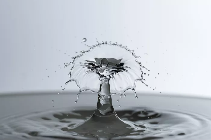 Waterzuil met een klokvormig scherm dat in druppeltjes uiteenvalt, in grijze tinten