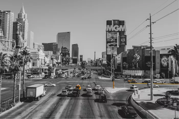 Drukke Strip in Las Vegas met auto's, palmbomen en hoteltorens, in zwart-wit met gele taxi's