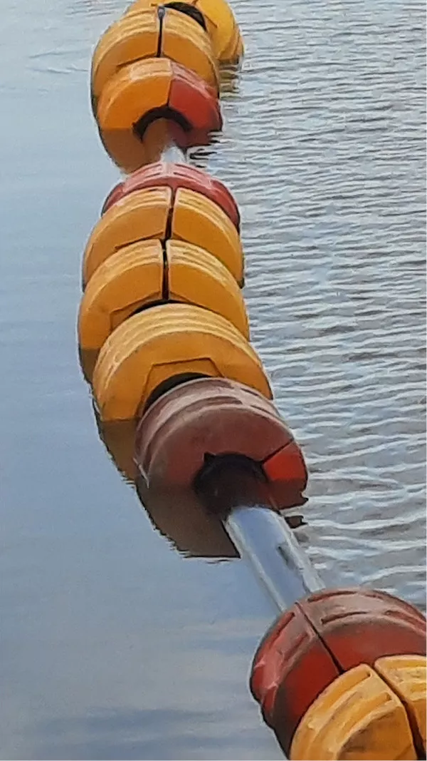 Rij gele en rode boeien op een buis in grijsblauw water