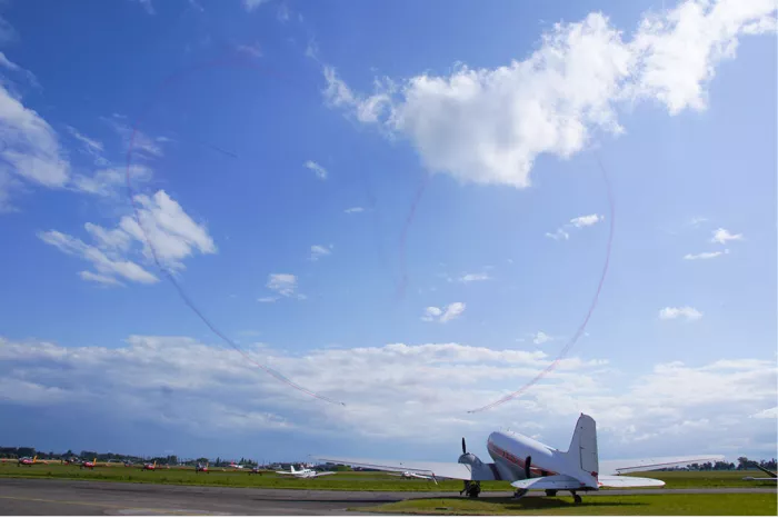 Rookhart in de blauwe lucht boven een vliegveld met een oud propellervliegtuig