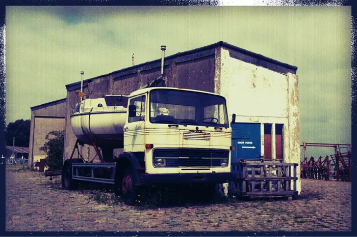 Oude vrachtwagen met tank voor een loods in een jachthaven, met vintage rand