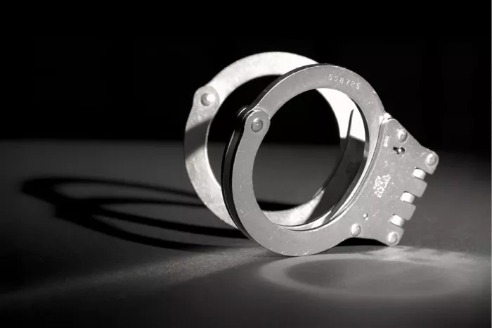 Metalen handboeien op een donkere ondergrond met een ronde schaduw