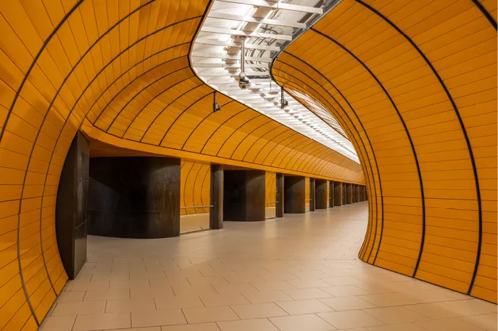 Verlaten oranje metrogang met gebogen wanden en een witte lichtstrook aan het plafond