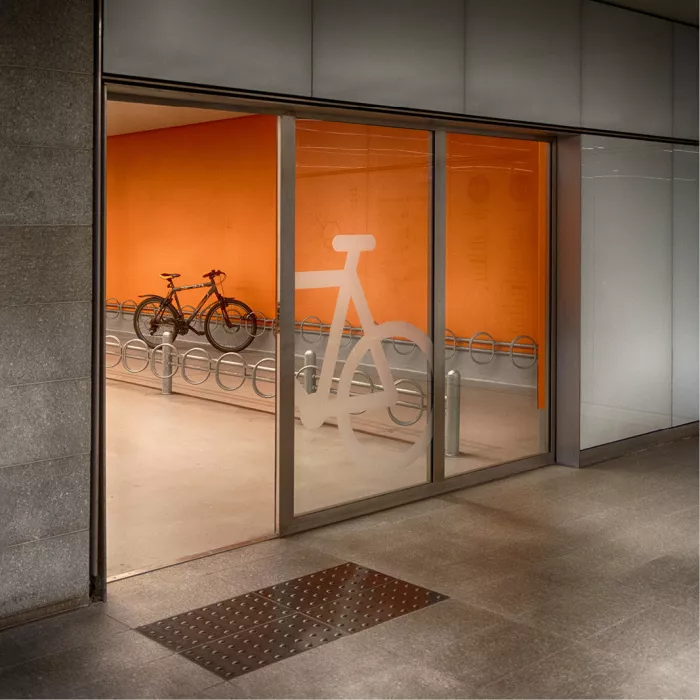 Glazen deuren met fietssymbool en één fiets in een rek tegen een oranje wand