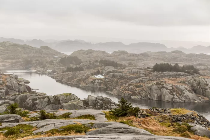 Rotsachtige kust met een stille inham en mistige bergen in de verte