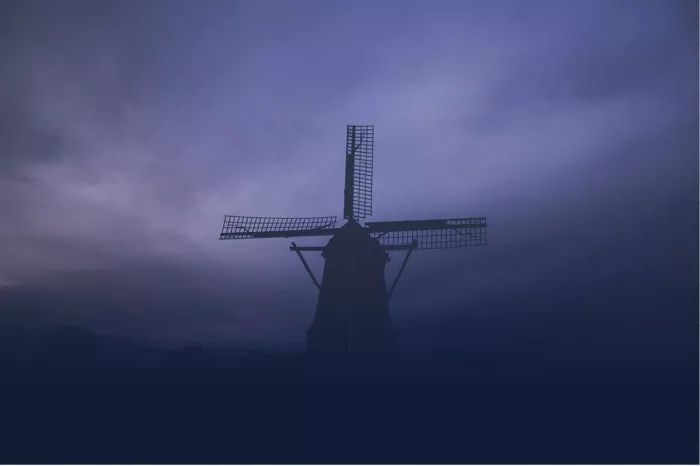 Silhouet van een windmolen in dichte blauwe mist