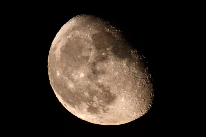 Bijna volle maan met kraters in detail tegen een zwarte hemel