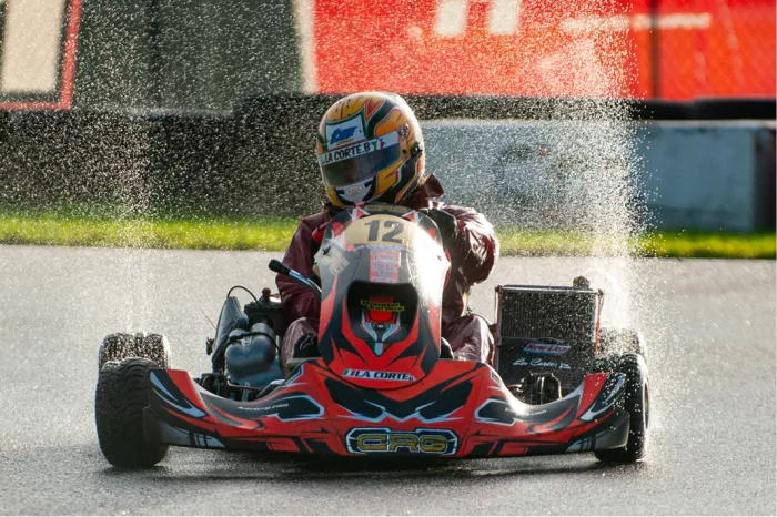 Rode kart die over een nat wegdek op de kijker afrijdt met opspattend water