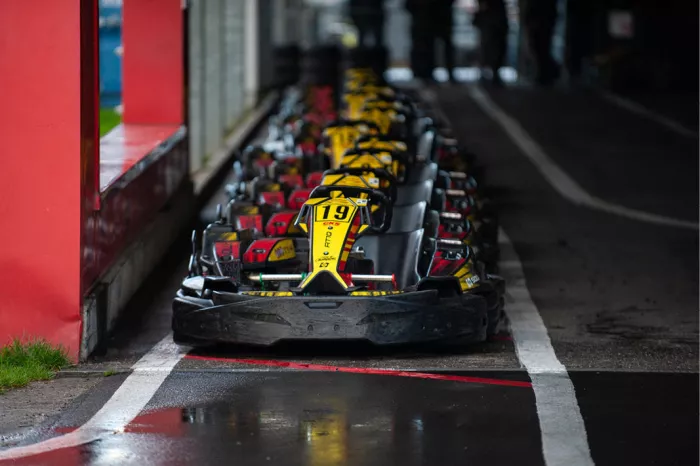 Rij zwart-gele karts klaar voor de start langs een nat circuit