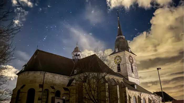 Kerk van Merchtem met klokkentoren onder een sterrenhemel bij nacht