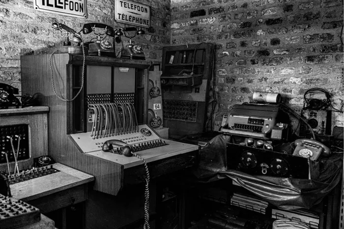 Historische telefooncentrale met schakelbord, oude telefoons en bordjes Telefoon tegen een bakstenen muur, in zwart-wit