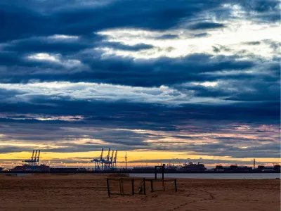 Dramatische wolken boven strand en haven, de foto